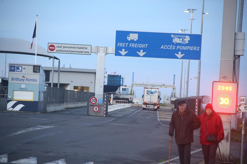 Vue sur le terminal de ferrys. Deux personnes âgées marchent au premier plan. 