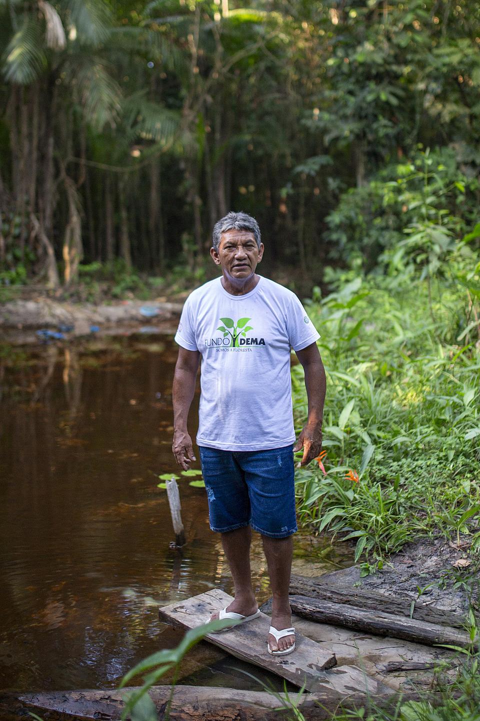Un homme debout devant une rivière dans la forêt.