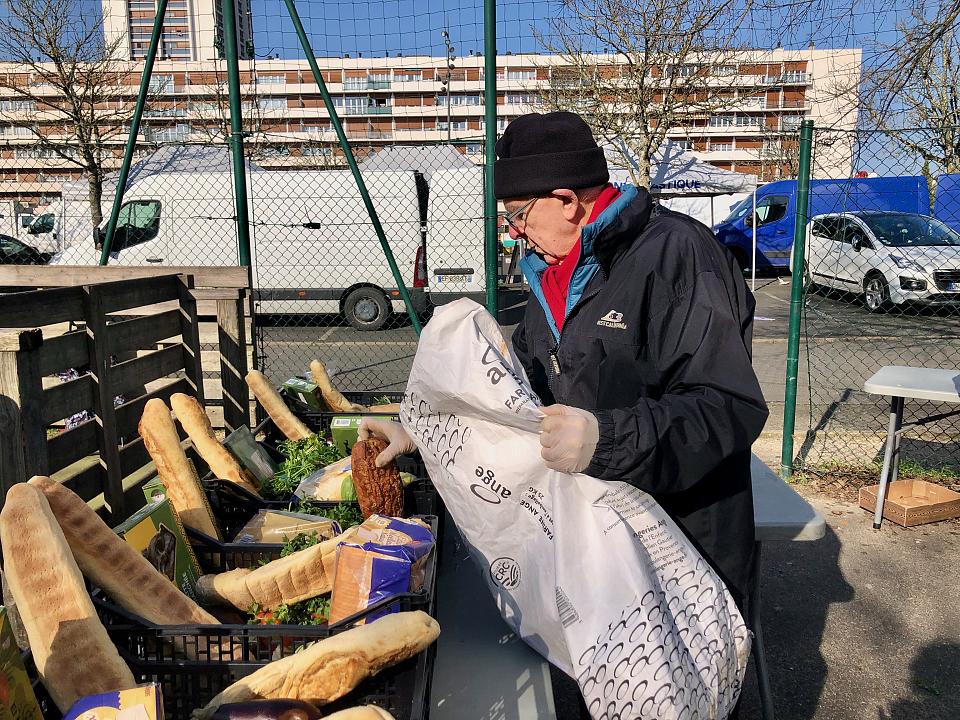 Un homme âgé devant des stands d'un marché en plein air