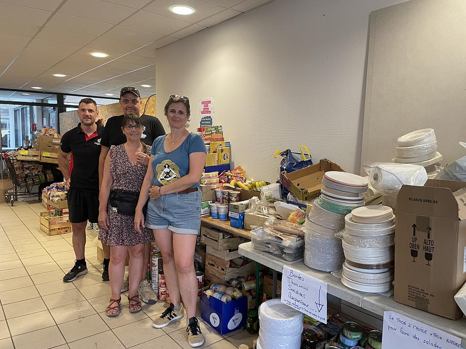 Quatre personnes debout devant des tables de denrées alimentaires. 