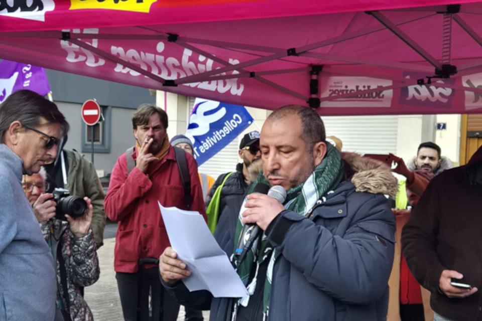 Un homme parle dans un micro lors d'un rassemblement. 