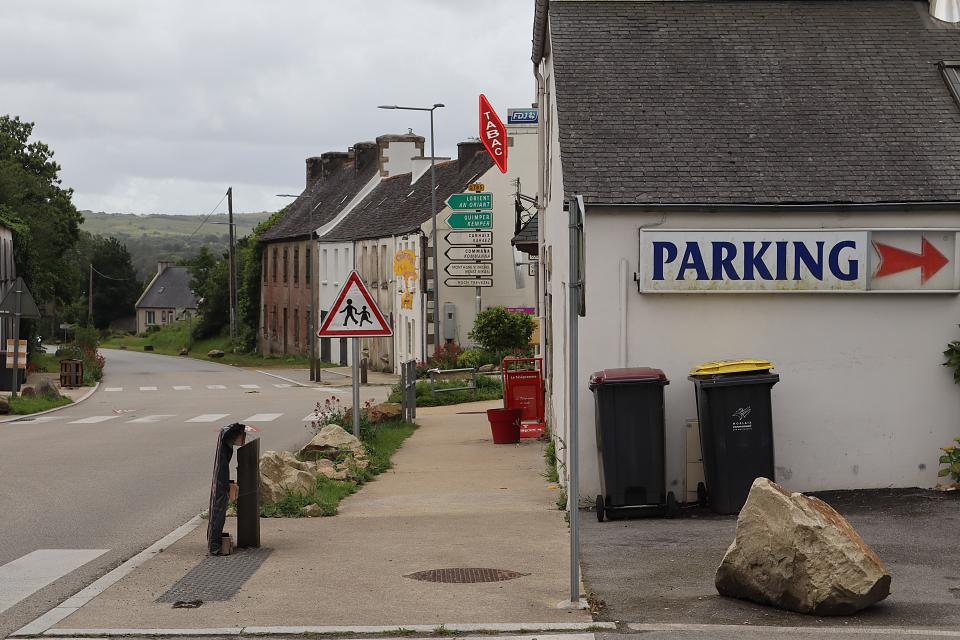 L'entrée d'un village avec un bureau de tabac et, au loin, la campagne.