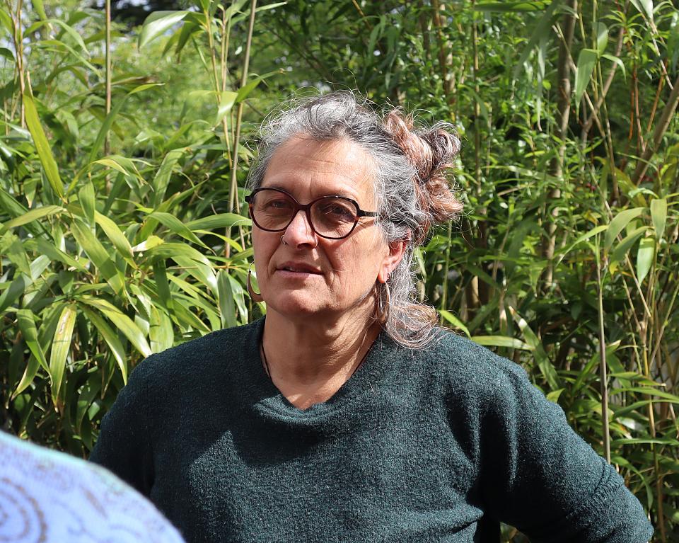 Une femme pose devant de la végétation.