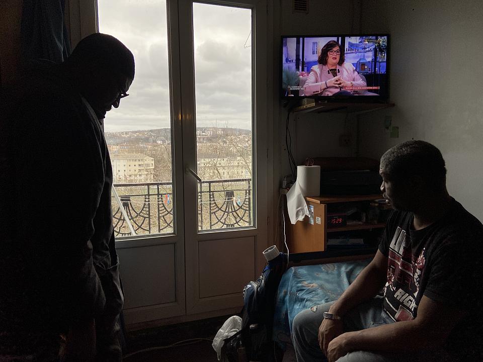 Oumar Diakité (à gauche), dans la chambre de Moussa Bakayoko (à droite). Au pied de la fenêtre, le sol s'est affaissé. Une planche de bois recouvre le trou qui le sépare de la chambre du bas.