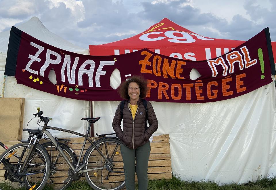 Cristiana Vandame devant une banderole "zone mal protégée" sur la Zad.