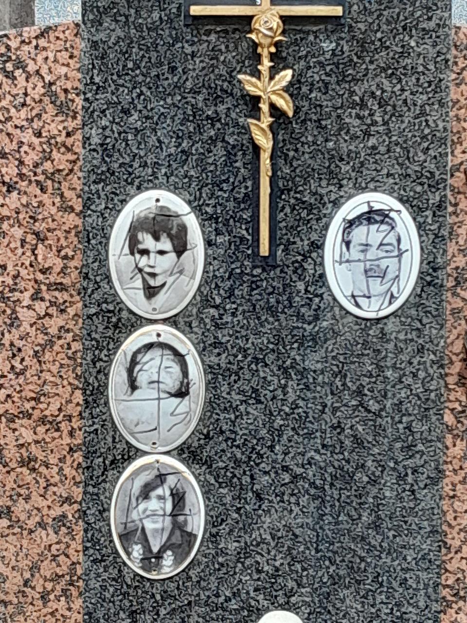 Quatre portrait en noir et blanc sur une tombe sont recouverts de croix gammées noire dessinées dessus.
