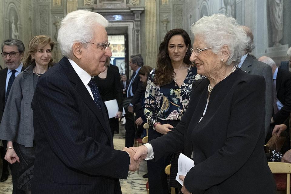 Le président italien serre la main à Liliana Segre, 89 ans, dans un hall entouré de personnes.