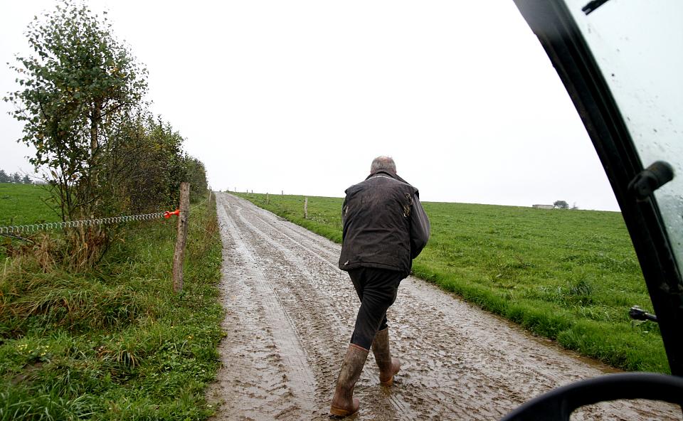 Un agriculteur en bottes sur un chemin de terre