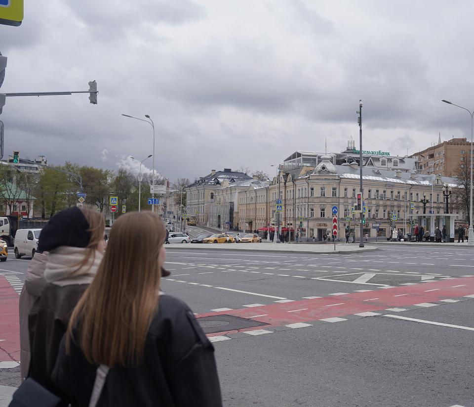 Deux jeunes femmes vues de dos attendent à un carrefour.