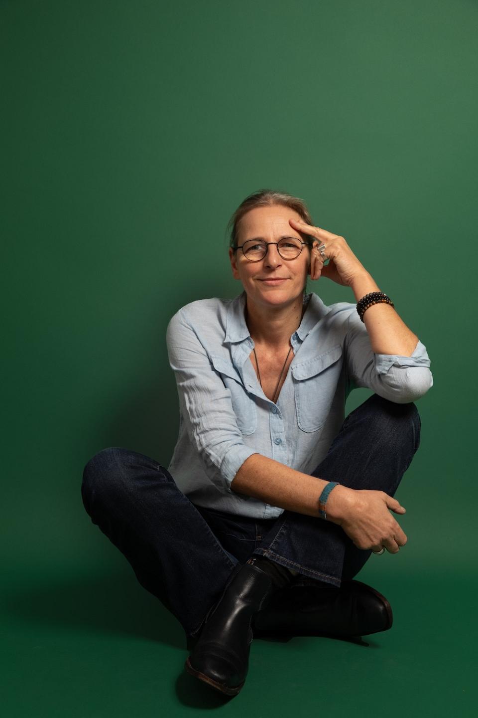 Une femme est assiste en tailleur sur un fond vert