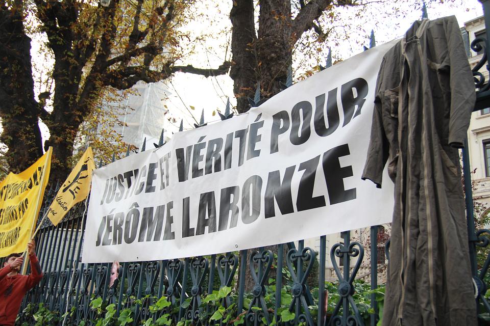 Une combinaison de travail est accrochée aux grilles de la préfecture aux côtés de la banderole "justice et vérité pour Jérôme Laronze"