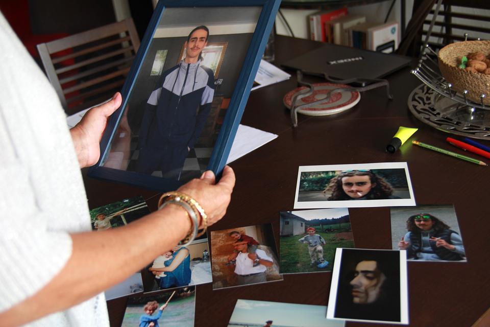 des mains tiennent un cadre de photo sur lequel s'affiche une jeune personne d'une vingtaine d'années.