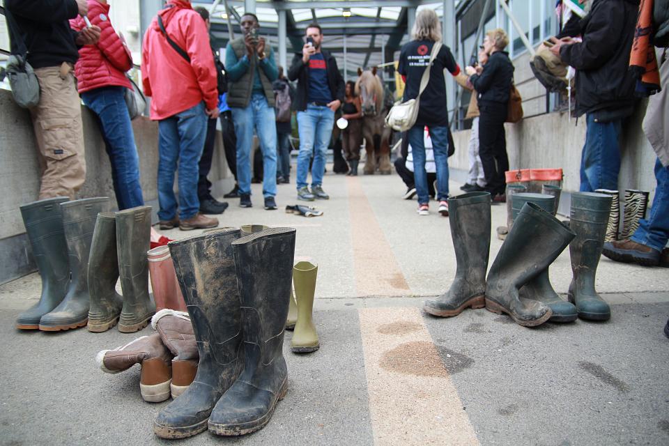 Des paires de bottes disposées devant l'entrée de la cité administrative de Mâcon.
