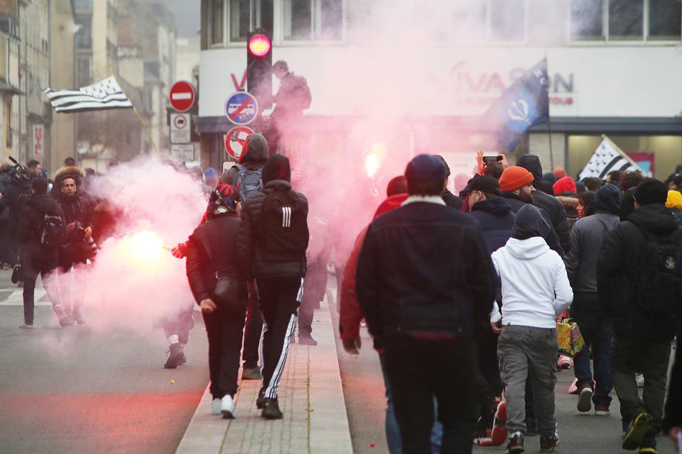 Des jeunes manifestants dans les rues de Rennes entre des fumigènes rouge. 