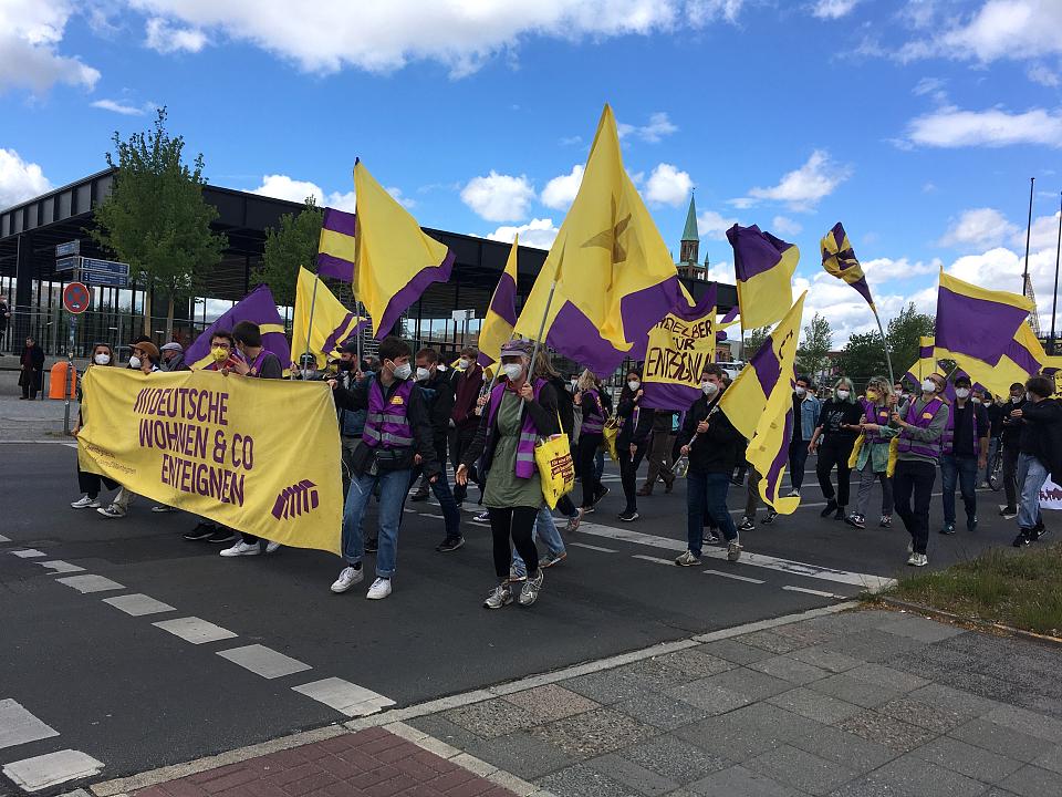 Une manifestation à Berlin. Les manifestants tiennent des drapeaux jaune et violet. 