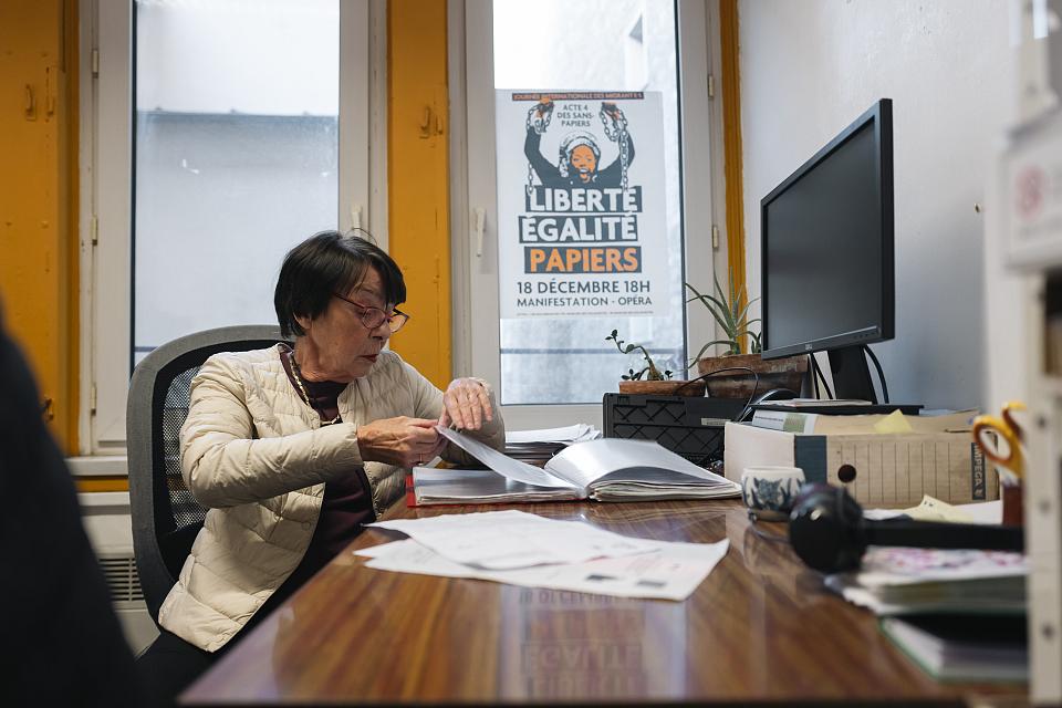 Une femme à un bureau consulte des documents. 