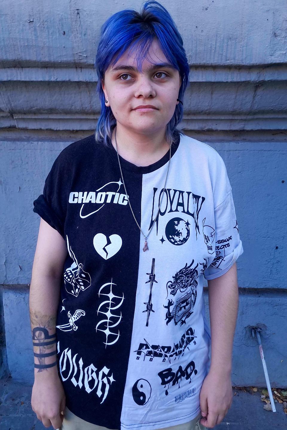 Une jeune personne aux chevuex bleus, debout, le regard vers la gauche.