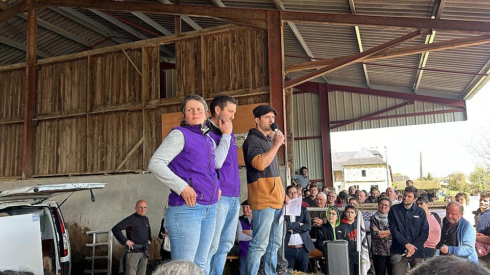trois personnes prennent le micro sur une ferme et font face à la foule