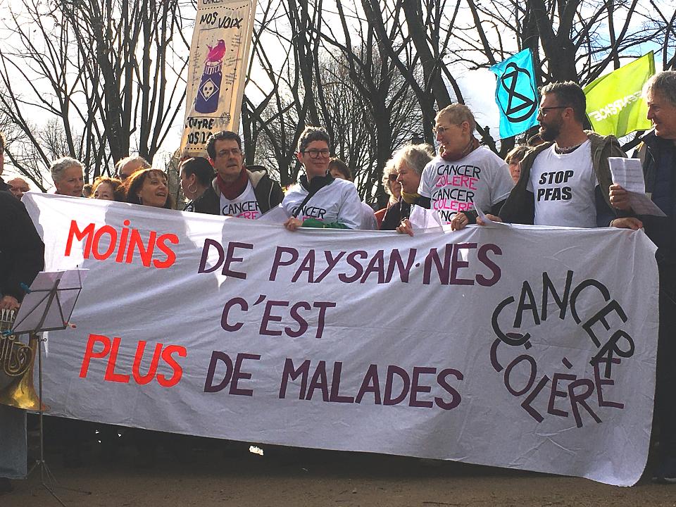déploiement de la banderole "moins de paysan·nes c'est plus de malades" avec le sigle cancer colère