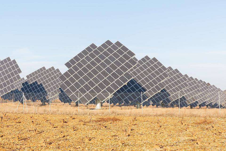 Plus de dix larges panneaux solaires surélevés, derrière des grillages, posés sur de la terre. 