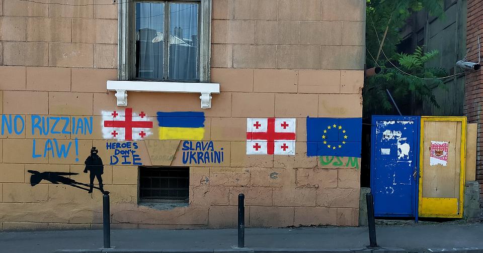 Des drapeaux géorgiens, ukrainiens te européens taggués sur un mur. Il est aussi taggé, « no russian law »