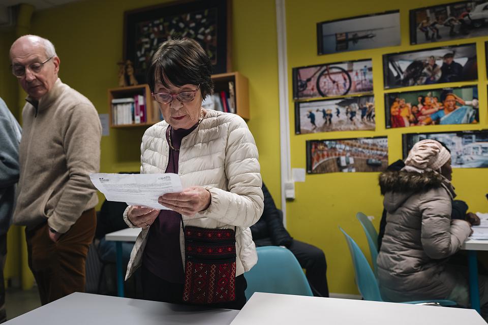 Un femme debout dans la permnacne regarde un document. 