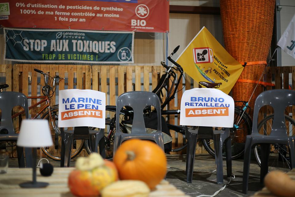 chaises arborant les noms de "marine le pen" et "bruno retailleau" comme "absent". Au premier plan, des courges, au dernier plan le drapeau jaune du collectif de soutien aux victimes des pesticides de l'Ouest, ainsi que la banderole "stop aux toxiques"