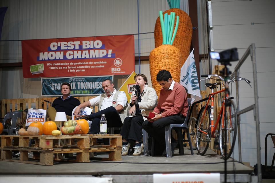 quatre femmes et hommes prennent la parole sur une estrade entourée d'une banderole "c'est bio mon champ"