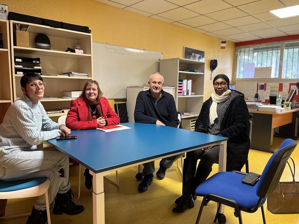 Quatre personnes assises à une table regardent l'objectif. 