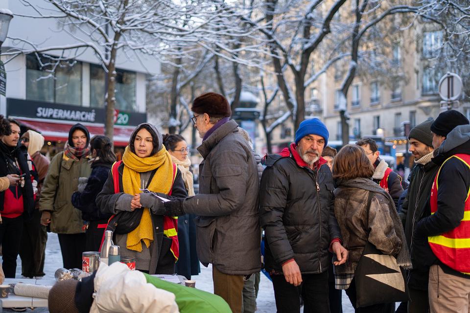  Des grévistes en bonnets, écharpes et manteaux groupés à l'extérieur du magasin. 