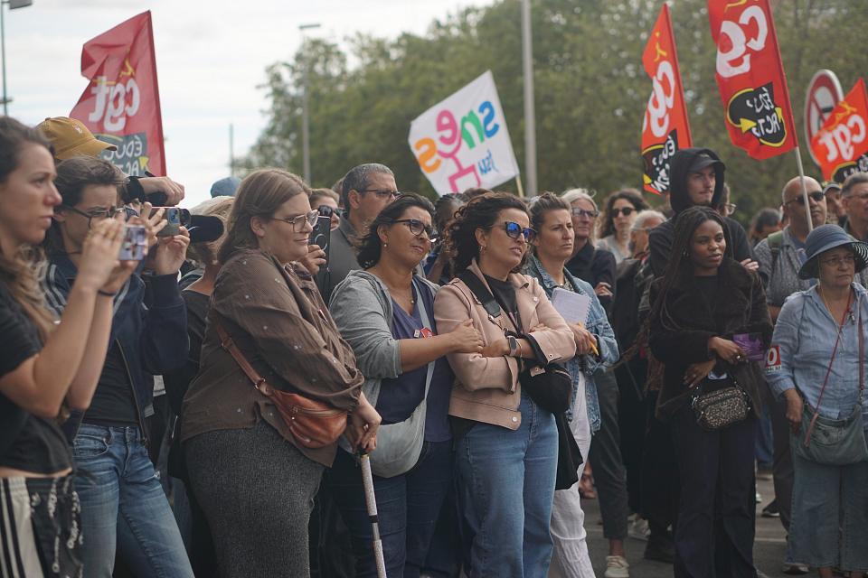 Des personnes rassemblées, on distingue des drapeaux syndicaux. 