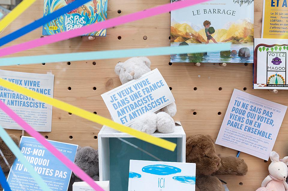 Un ours en peluche en vitrine tient une pancarte "Je veux vivre dans une France antifasciste et antiraciste".