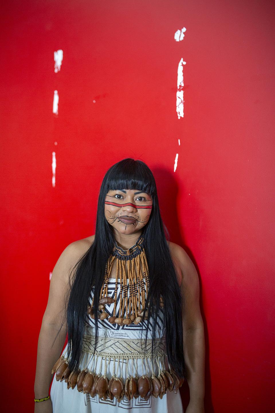 Une jeune femme souriante devant un mur rouge. 