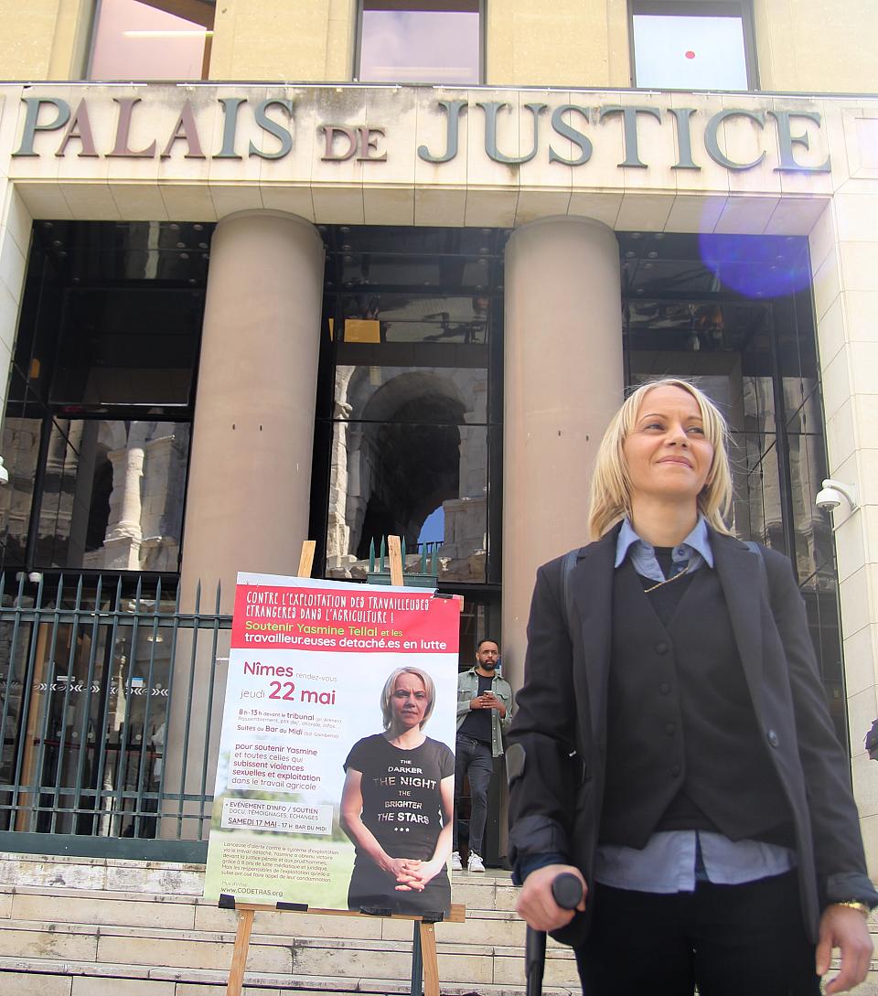 Une femme se tient debout devant l'entrée du Palais de justice. 