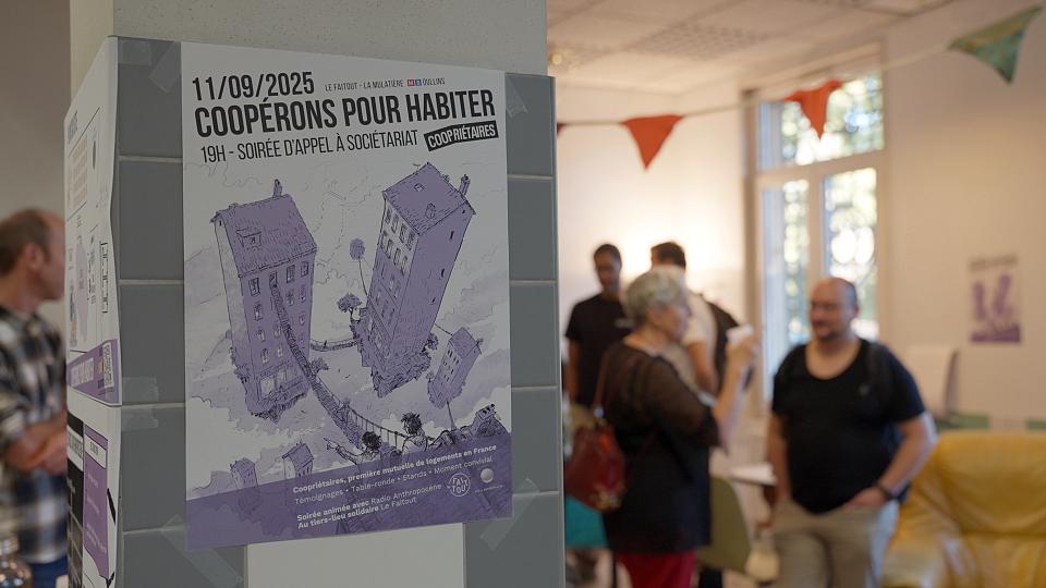 Une affiche "Coopérons pour habiter" collées sur un poteaux lors d'un événements où des personnes discutent débout au deuxième plan.