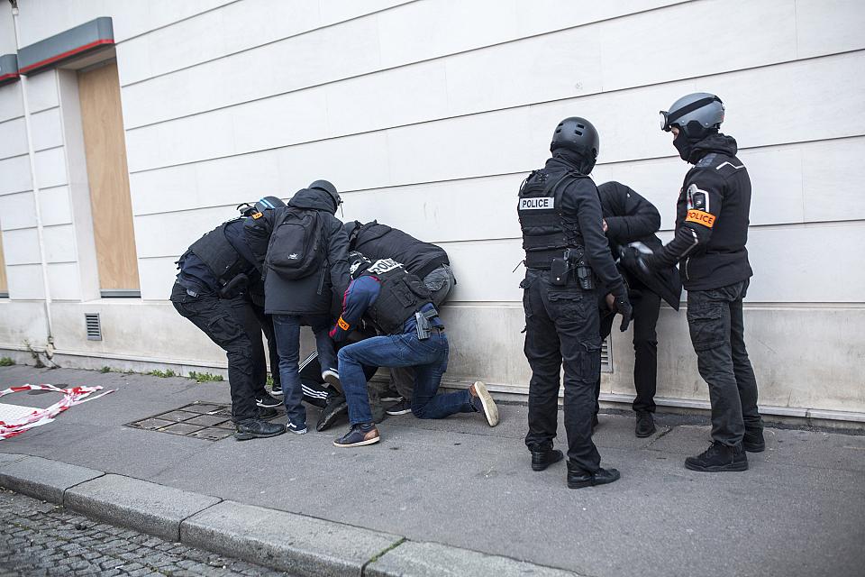 Des policiers dont certains en civil arrêtent deux personnes dans une rue.