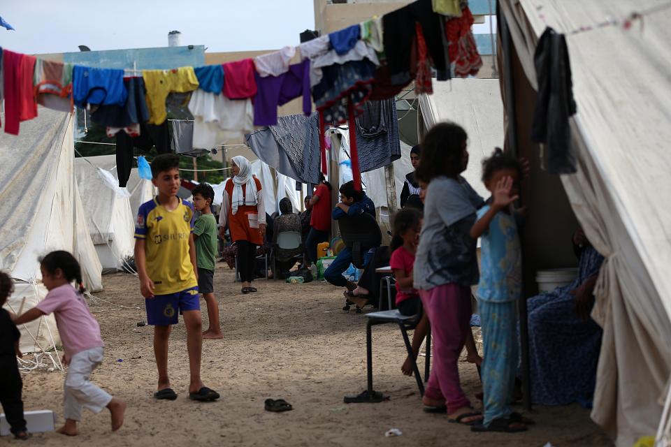 Des enfants parmi des allées de tentes