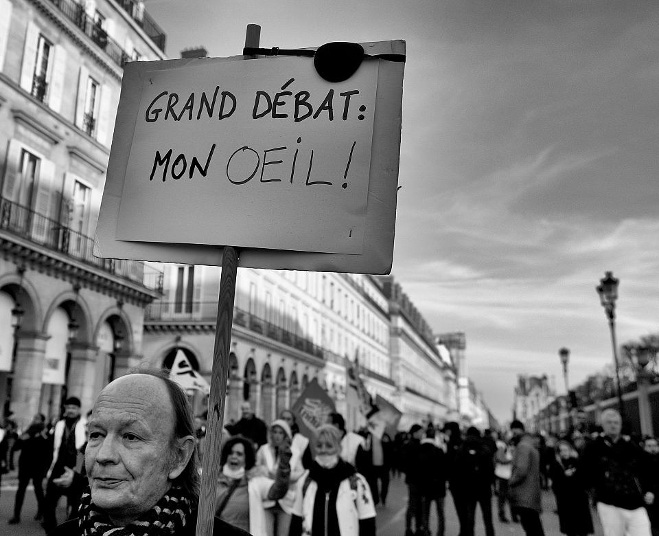 Un homme porte une pancarte "grand débat, mon oeil"