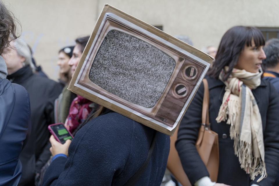 Une manifestante portant une télé en carton avec écran noir