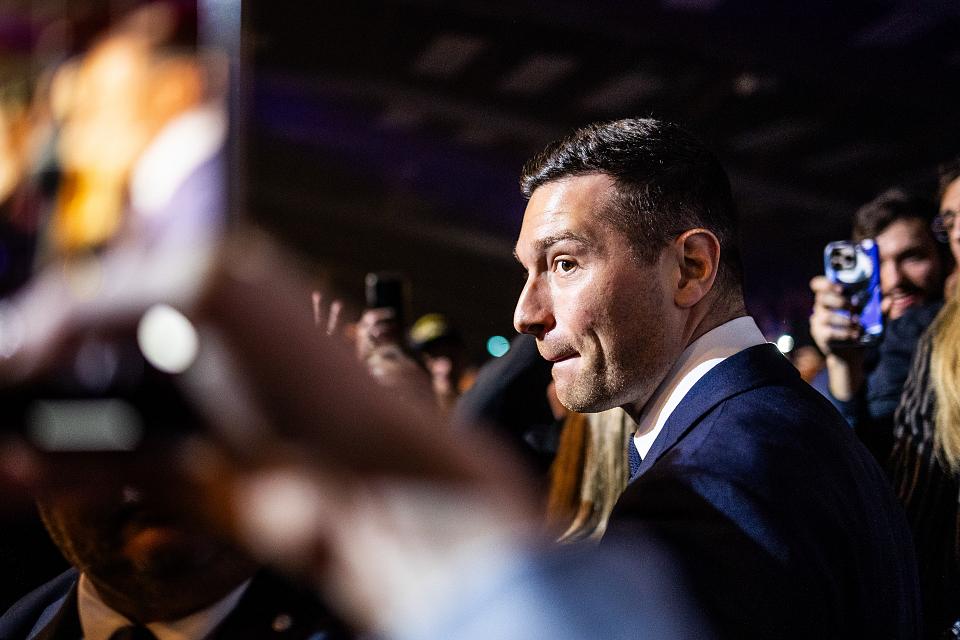 Regard d'un œil de Jordan Bardella vers une militante filmant avec son téléphone son arrivée au Palais des Expositions à Perpignan.