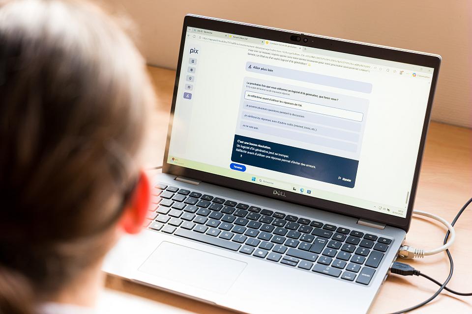 Un salarié est pris en photo de dos face à un écran d'ordinateur portable.
