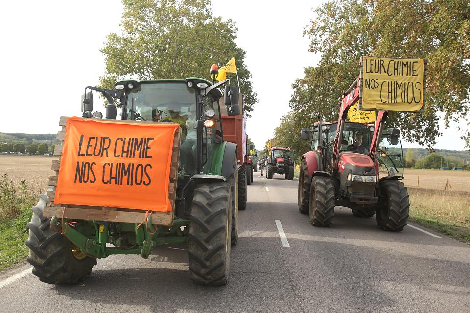 des tracteurs brandissent des banderoles "leur chimie, nos chimios" sur une route