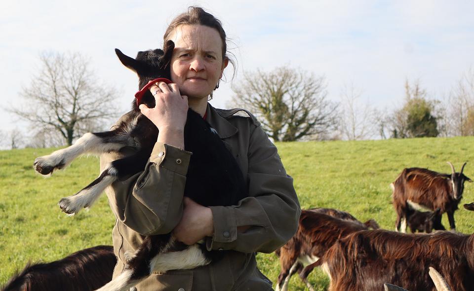 Une femme portant une petite chèvre dans ses bras.