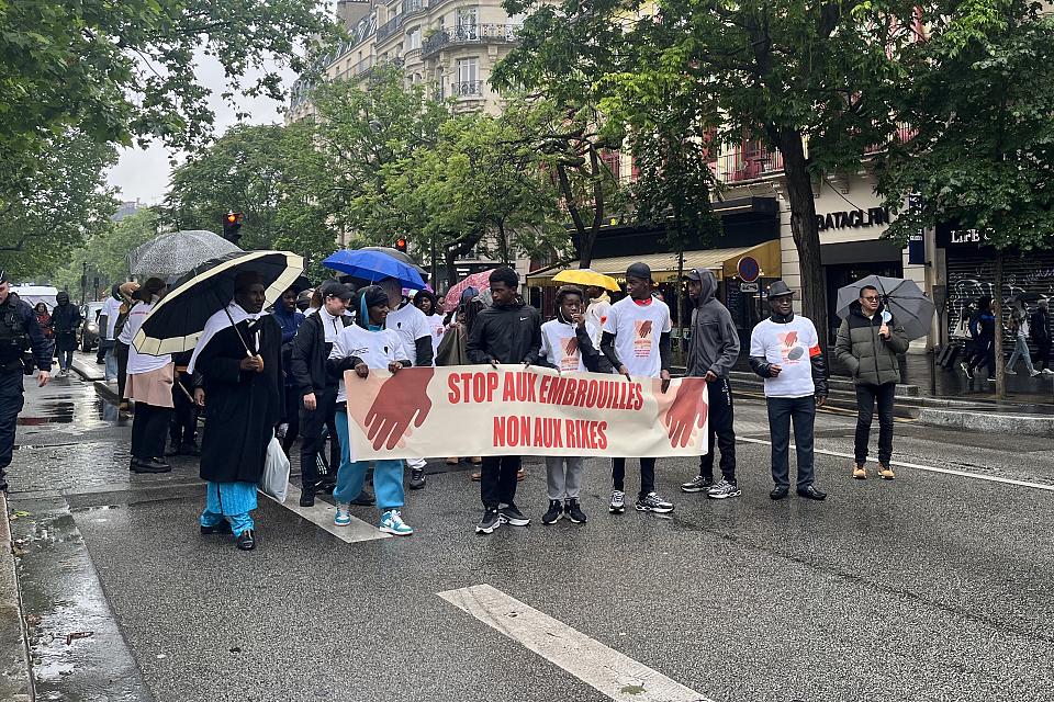 Des personnes marchent dans la rue avec une banderole "Stop aux embrouilles. Non aux rixes"