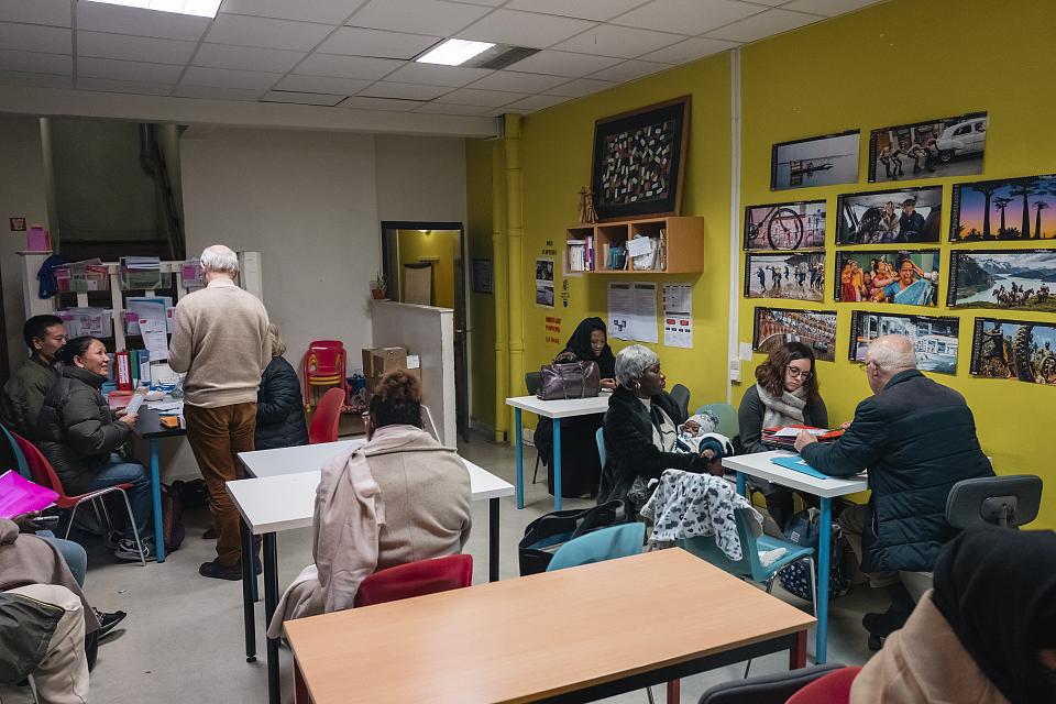 Vue de la salle de permanence où des bénévoles reçoivent des personnes étrangères 