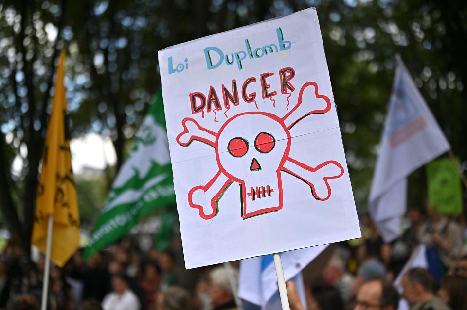 Une pancarte avec le message « Loi Duplomb danger », avec un dessin d'une tête de mort. 