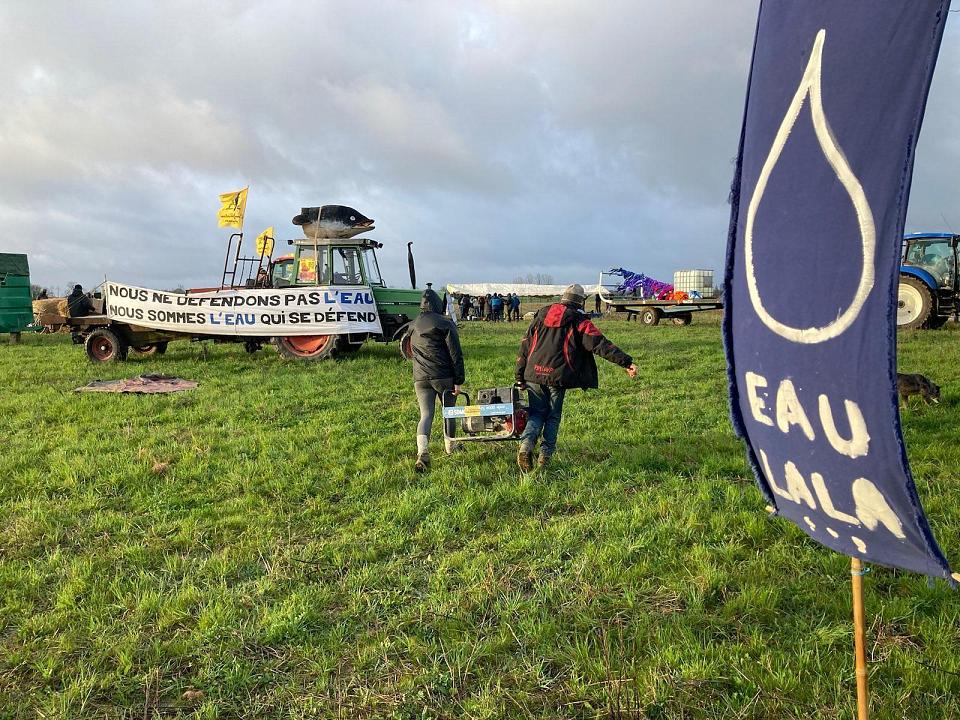 banderole "eau la la" et "nous ne défendons pas l'eau, nous sommes l'eau qui se défend" avec un drapeau de la confédération paysanne sur un tracteur