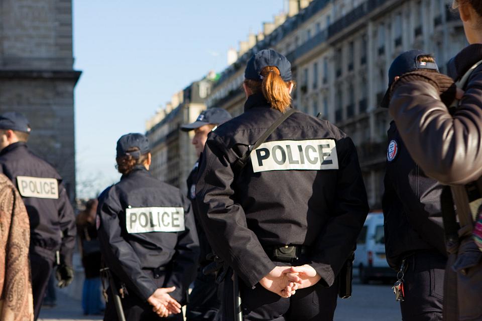 Des policiers, de dos, dans une rue parisienne