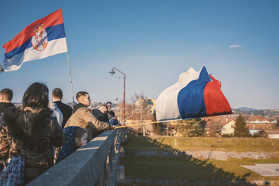 Une foule sur un pont, on voit deux drapeaux serbes, l'un brandi par un homme et l'autre au-dessus des gens