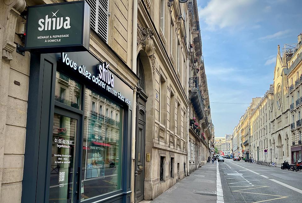 Photo d'une rue parisienne, avec en premier plan une enseigne Shiva.